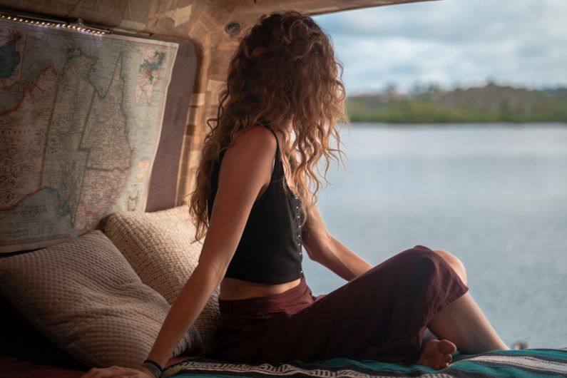 Budget Fitness - woman wearing black spaghetti strap top sitting viewing body of water