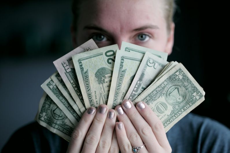 Budget Gift - person holding fan of U.S. dollars banknote