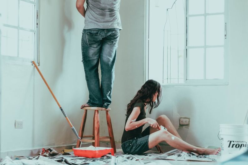 DIY Home - woman in gray tank top and blue denim jeans sitting on bed