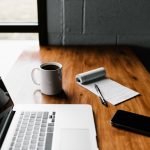 Tech Luxury - MacBook Pro, white ceramic mug,and black smartphone on table