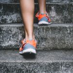 Luxury Fitness - person wearing orange and gray Nike shoes walking on gray concrete stairs
