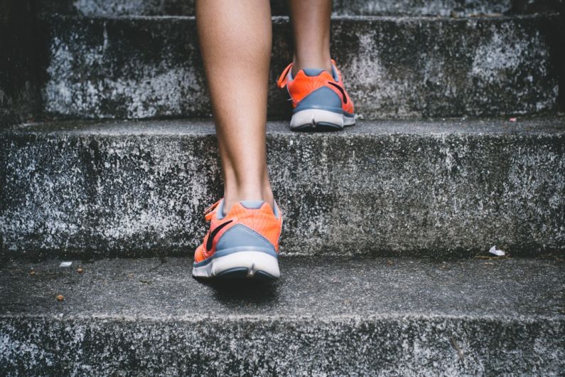 Luxury Fitness - person wearing orange and gray Nike shoes walking on gray concrete stairs
