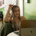 Student Discount - a woman with dreadlocks sitting in front of a laptop computer