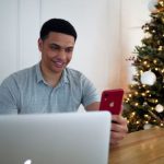 Electronics Sale - man in blue polo shirt holding red iphone 7 plus