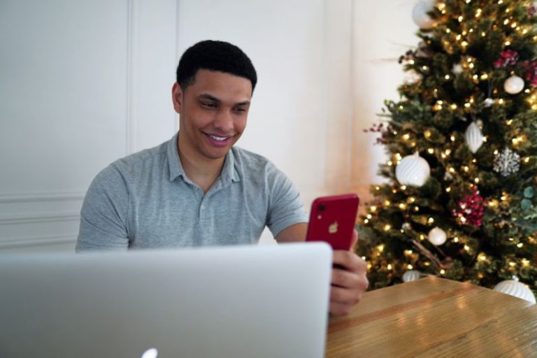 Electronics Sale - man in blue polo shirt holding red iphone 7 plus