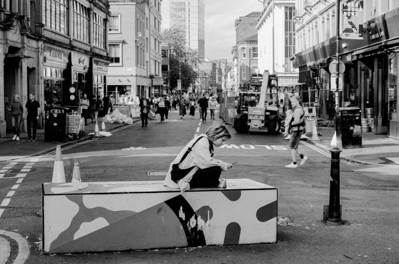 Marketplace Diversity - a woman sitting on a box in the middle of a street