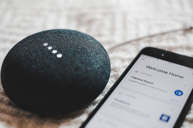 Smart Home - turned-on charcoal Google Home Mini and smartphone