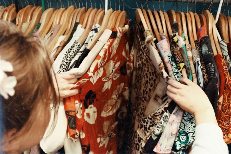 Vintage Fashion - person holding assorted clothes in wooden hanger