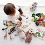 Educational Toy - boy sitting on white cloth surrounded by toys