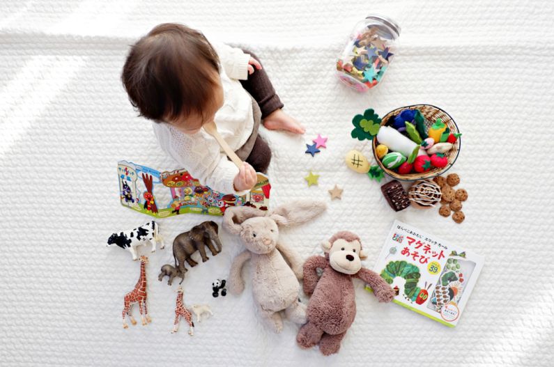 Educational Toy - boy sitting on white cloth surrounded by toys