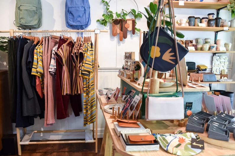 Ethical Fashion - assorted-colored clothes on rack near brown wooden table